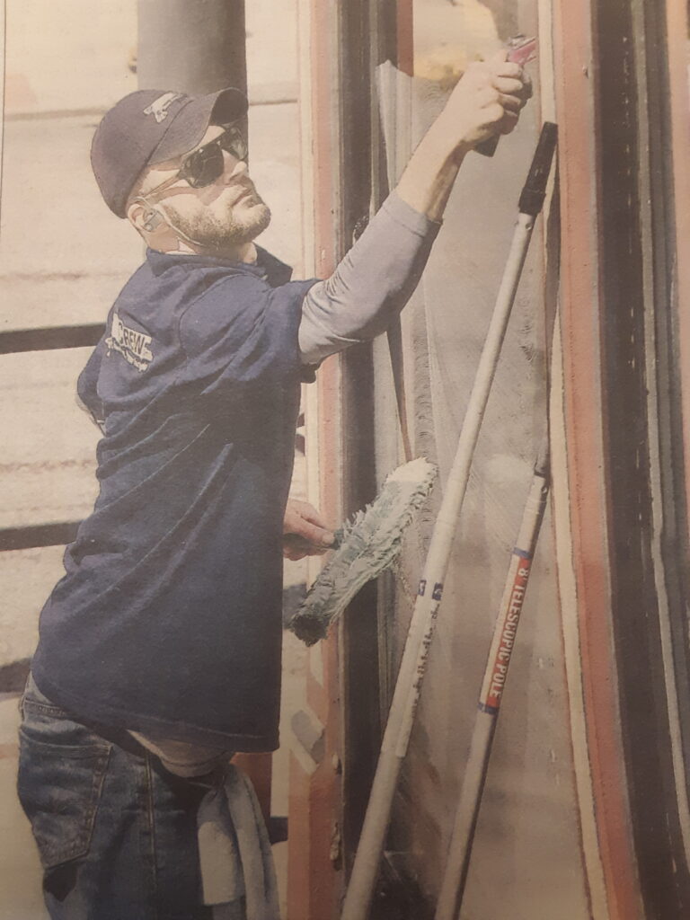 A man in blue shirt painting on wall.