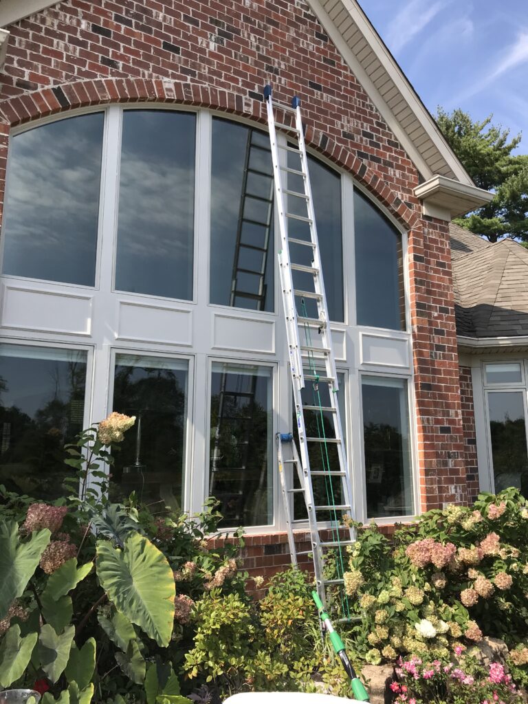 A ladder in front of a house with windows.