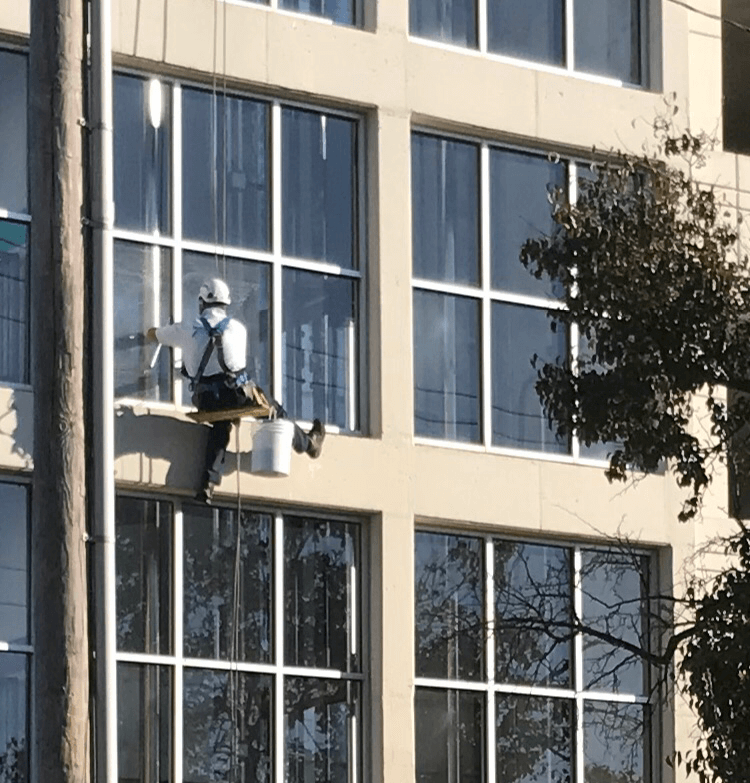 A man is on the side of a building while hanging from ropes.