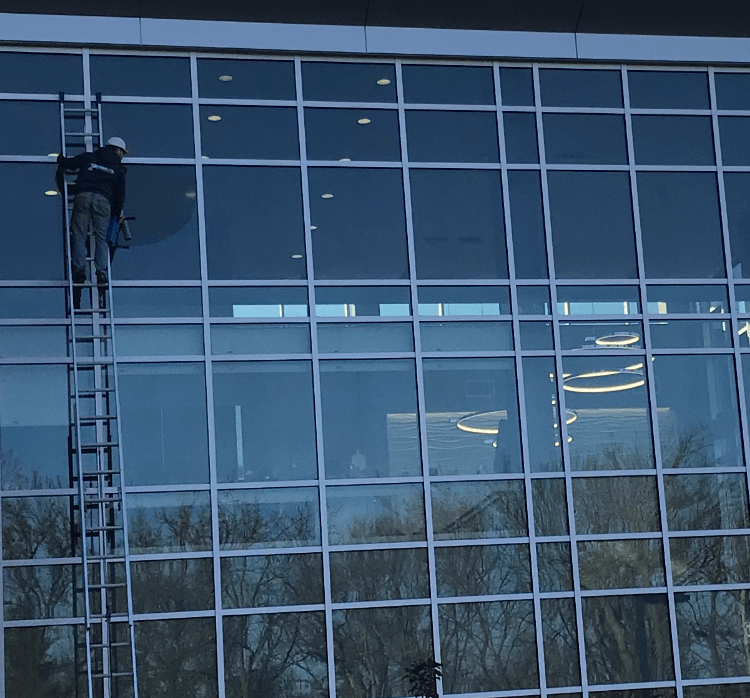 A man on a ladder cleaning windows of a building.